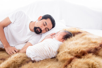 Selective focus of Father Sleeping with newborn baby in bed. Asian little baby lying wrapped in thin white cloth on brown wool. Dad sleeping and touch adorable toddler with love and care.