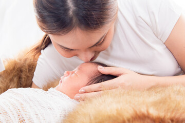Close up of beautiful asian young mother kissing newborn while baby deeply sleeping with happiness....