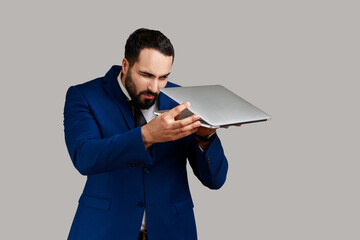 Bearded man opening and taking glance at laptop display, trying to find out private information and...