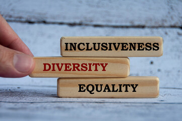 Inclusiveness, diversity and equality text on wooden blocks with wooden cover background. Business...