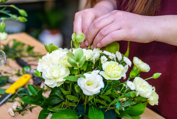 The hands of woman florist making a bouquet of mixed unusual original flowers