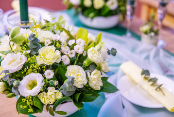  beautifully decorated festive table with plates and glasses and a bouquet of flowers in a restaurant