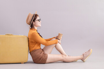 Traveler woman in casual clothes sitting with outstretched legs lean on yellow suitcase and holding...