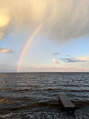 Rainbow stretching from the Saint-Jean Lake, Quebec, to a rain cloud during the golden hour of a...