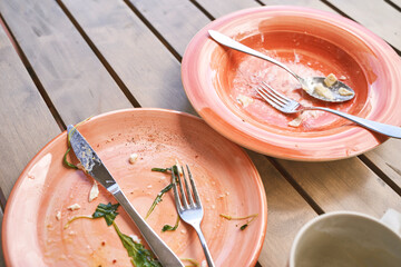 Two dirty plate in outdoor cafe after dinner. Messy dishes breakfast. Lunch casual atmosphere. Lifestyle cozy morning. No people. Knife and fork, spoon. Nobody leftover