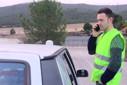 Emergency light V16 beacon on roof of damaged vehicle. Worried Driver calling car insurance. Help flash, mandatory to replace triangles in Europe. DGT Spain. High quality photo