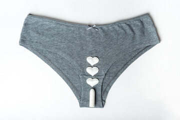 Gray women's panties and white cotton sanitary tampon and hearts as mestrual drops on a white...