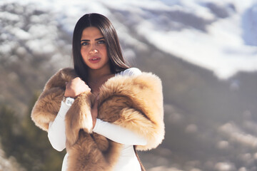 Young Hispanic dark-haired female wearing warm clothes in the snow-capped mountains of Andorra - obrazy, fototapety, plakaty