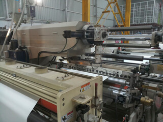 Kolkata, West Bengal, India - 12th January 2019 : Extruder and roller running for coating polyethylene , PE on paper, for making paper cups.
