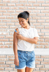 Smiling Latin woman looking at her shoulder after being vaccinated against the Covid 19 flu. Second dose. - obrazy, fototapety, plakaty