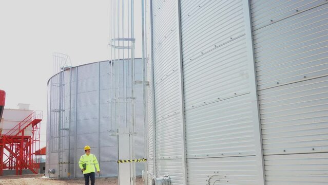 Engineer using laptop examine the construction of water tanks  steel metal sheet for tap water water storage of industrial estate. Utilities of industry.