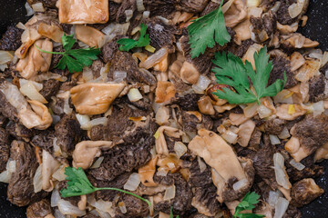 Fried morel mushrooms in olive oil in a frying pan,close up