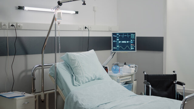 Nobody In Hospital Ward For Resuscitation And Healthcare. Empty Emergency Room With Medical Equipment, IV Drip Bag And Heart Rate Monitor For Intensive Care And Assistance For Recovery