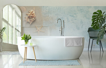 Interior of light room with mirror and bathtub near wall with printed sea beach