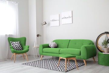 Interior of light living room with green sofa and armchair