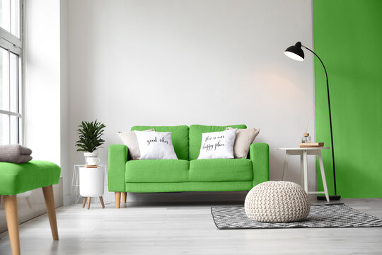 Interior of living room with green sofa, table, pouf and lamp