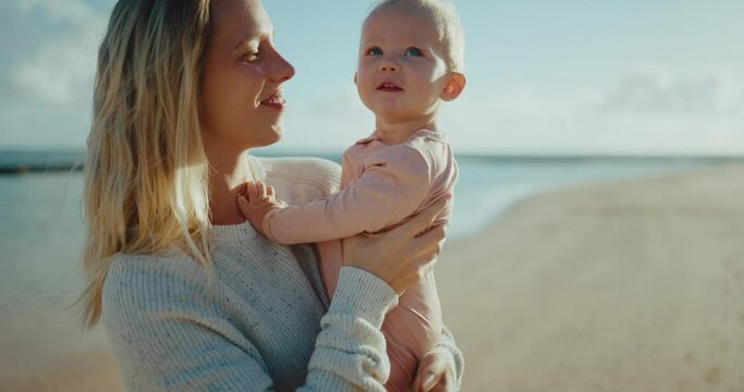 Mother and adorable young baby enjoying beautiful morning at the beach, motherhood family lifestyle
