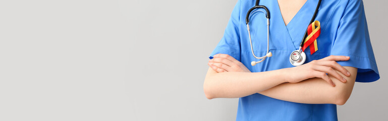 Female doctor with awareness ribbon and stethoscope on grey background with space for text. Hepatitis concept