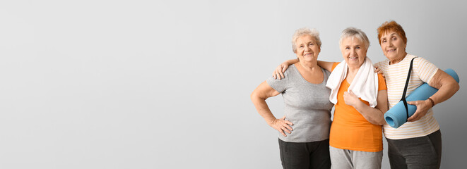 Elderly women holding yoga mat on light background with space for text