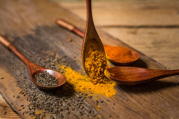 Spices cumin, red pepper, curry, and a wooden spoon