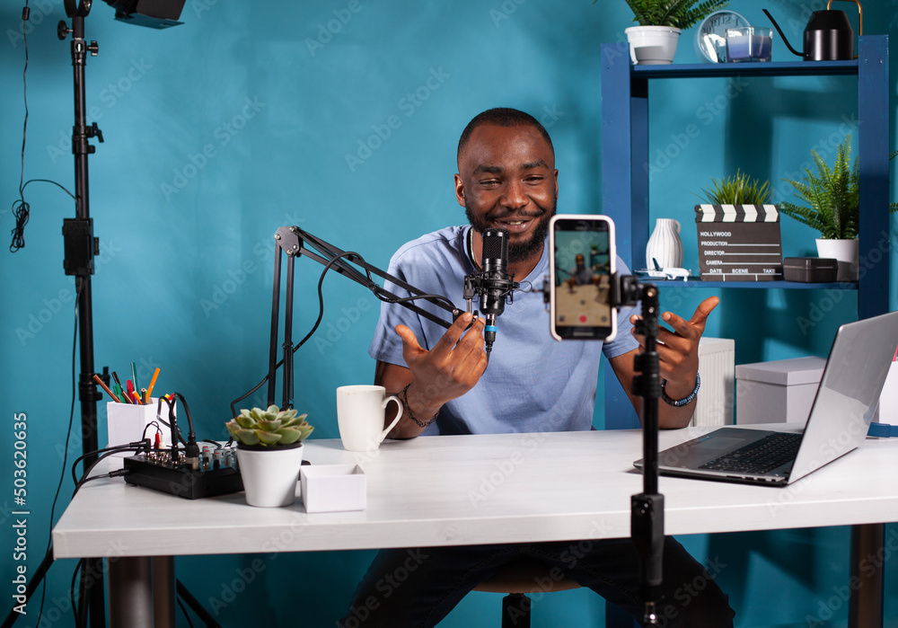 Poster content creator interacting with fanbase in studio looking at live video podcast setup sitting at de