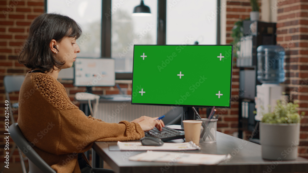 Poster woman working with horizontal green screen on monitor in startup business office. entrepreneur using
