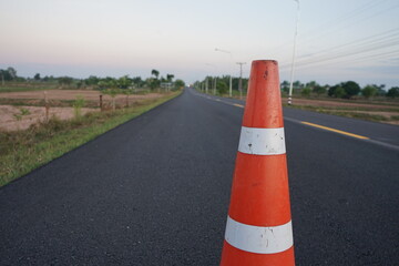 Red rubber cones are placed in the paved road.