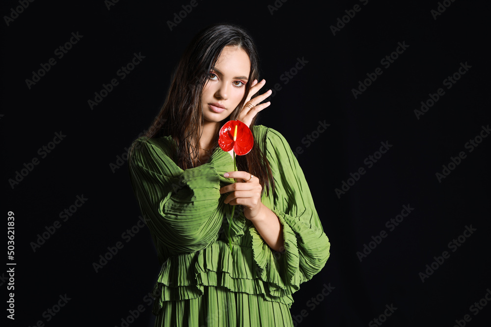 Wall mural Beautiful woman with wet hair holding anthurium flower on dark background