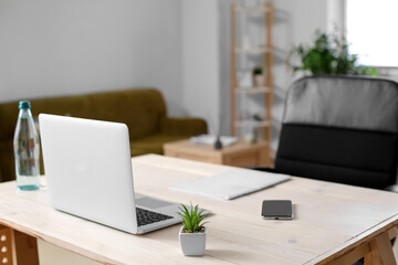 Workspace with modern laptop and mobile phone in light room