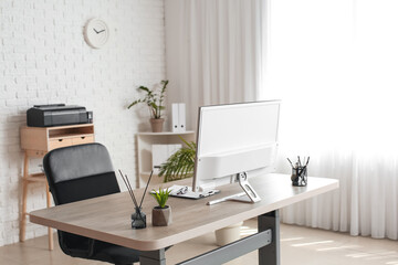 Comfortable workplace with modern computer, reed diffuser and houseplant in light room