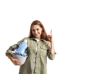 Beautiful woman with laundry and detergent pointing at something on white background