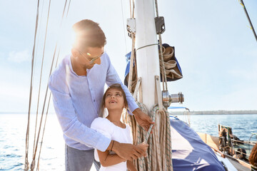 Happy young father with his little daughter resting on yacht