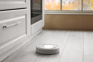 Modern robot vacuum cleaner near counter in kitchen