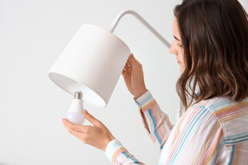 Woman changing light bulb in standard lamp at home