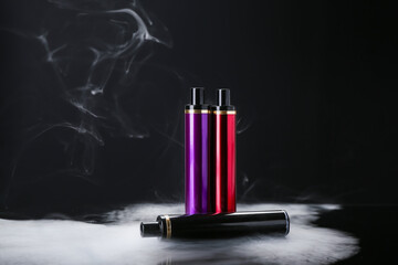 Disposable electronic cigarettes and smoke on dark background