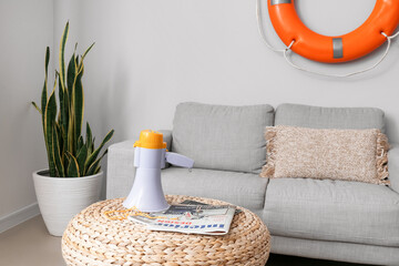 Megaphone with whistle and magazines on pouf in living room