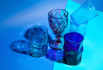 Stylish empty glasses on color background