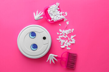 Modern robot vacuum cleaner with broom, scoop and paper pieces on pink background
