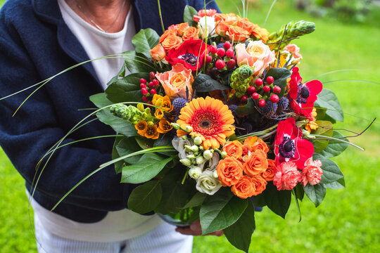 Geschenk für Muttertag, Geburtstag- ältere Dame hält wunderschönen bunten Blumenstrauss in fröhlichen Farben in den Händen