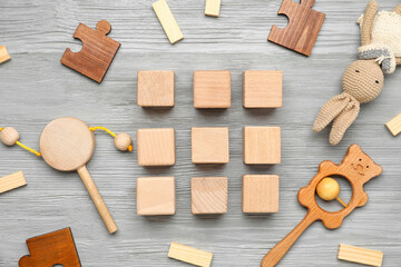 Cubes with baby toys on grey wooden background