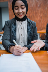 portrait of muslim businesswoman signing a contract with her partner during office meeting
