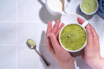 Matcha green tea latte on white concrete background with hard light, one cup of matcha drink in...