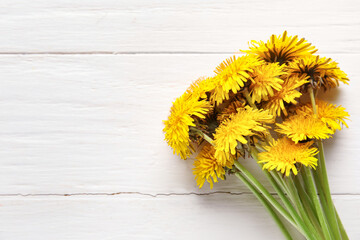 Yellow dandelions on white wooden background, closeup
