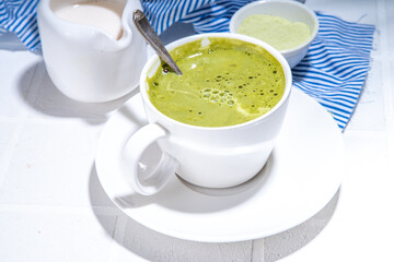 Matcha green tea latte on white concrete background with hard light, one cup of matcha drink in...