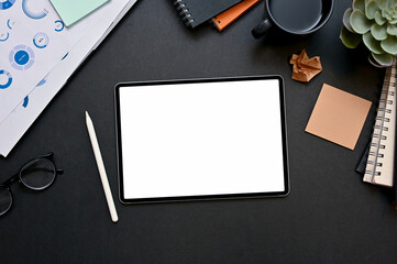 Modern business office workspace with digital tablet and essential supplies on black background.