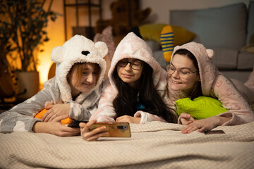 Group of teenage girls using a cellphone on the bedroom at home