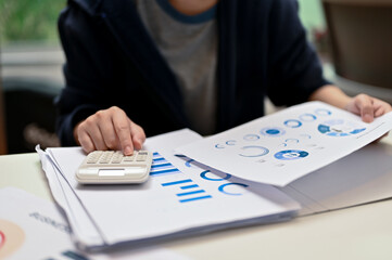 Female financial worker examining financial report at her office desk.