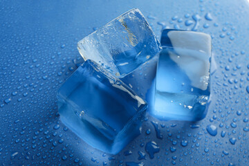 Ice cubes on wet blue background, close up