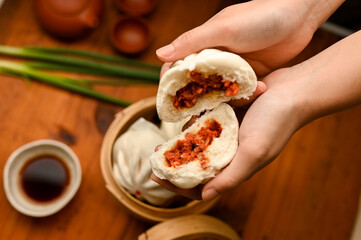 Above, Female hands with a tasty Chinese steamed pork bbq buns