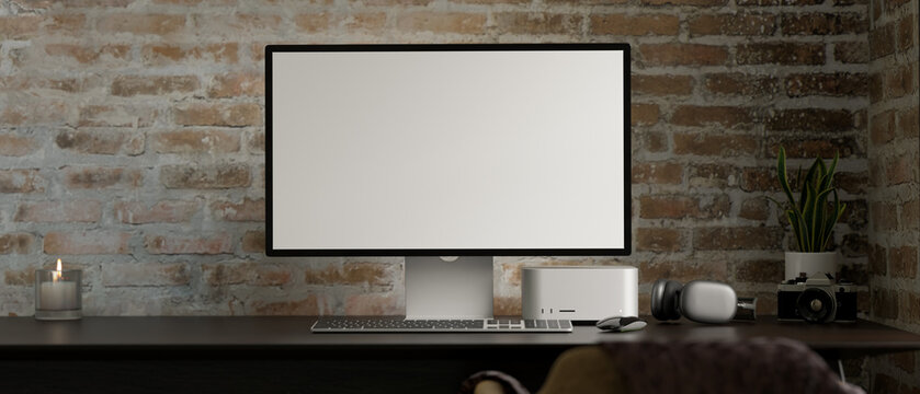 Computer mockup is stand on modern office desk workspace over classic brick wall.